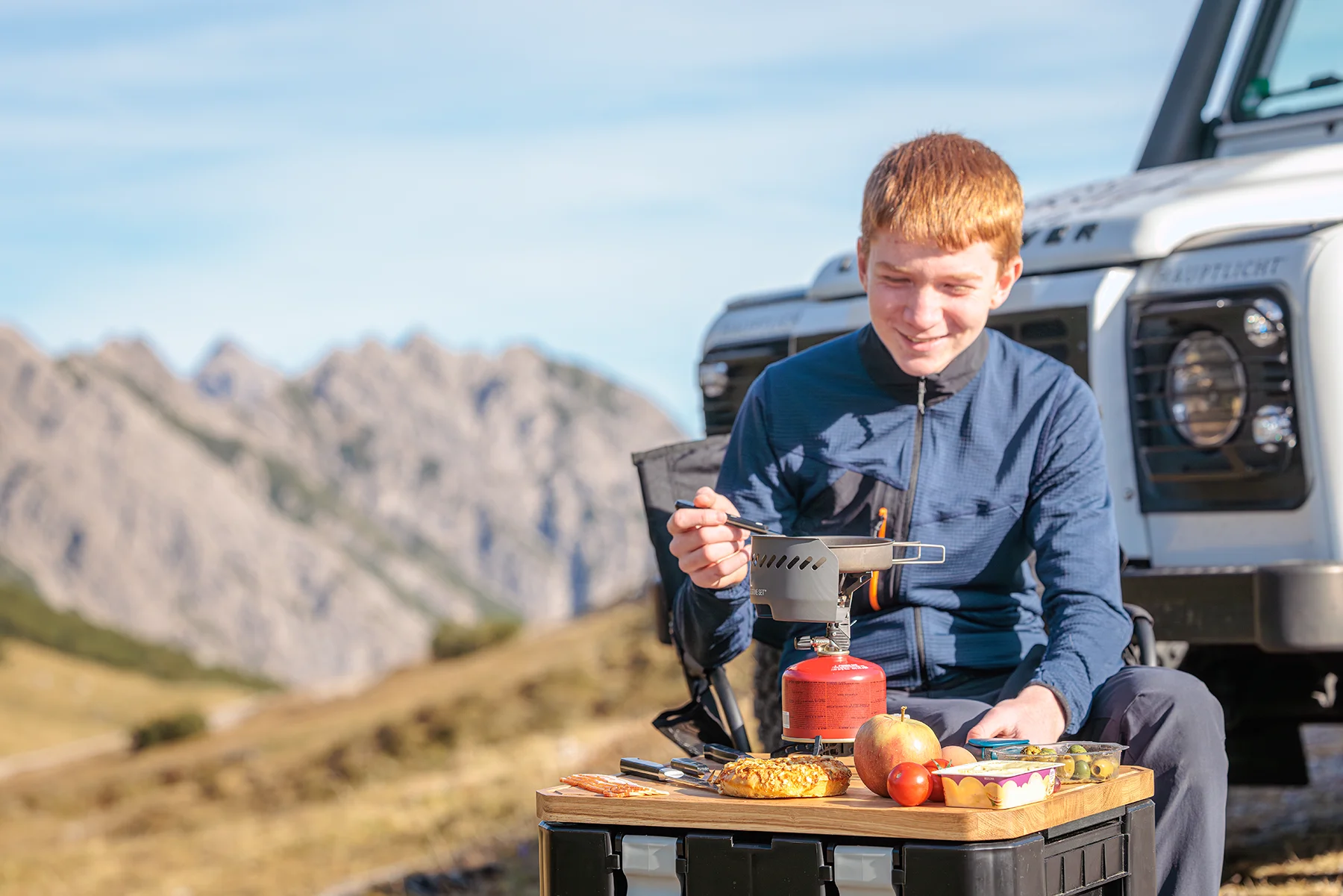 WOLFBOARD.pro aus massiver europäischer Eiche im Lifestyle-Einsatz beim Camping am See. Das Eichenholzbrett dient als stabiler Tischaufsatz auf der Front Runner Wolf Pack Pro Cargo-Box für Kaffeekanne, Becher und Verpflegung.